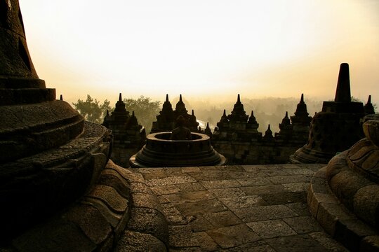 borobudur temple stupa silhouette stand stone terrace golden sunrise dawn mist horizon serene spiritual travel background