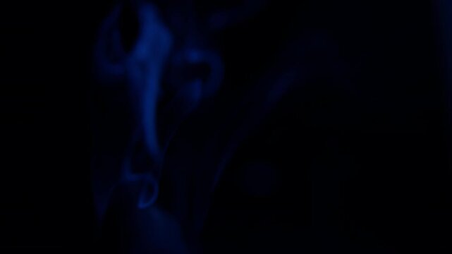 Blue smoke rising on a black background, creating an abstract and ethereal vapor effect. This slow, fluid movement of fog provides a versatile atmospheric element for motion graphics, transitions