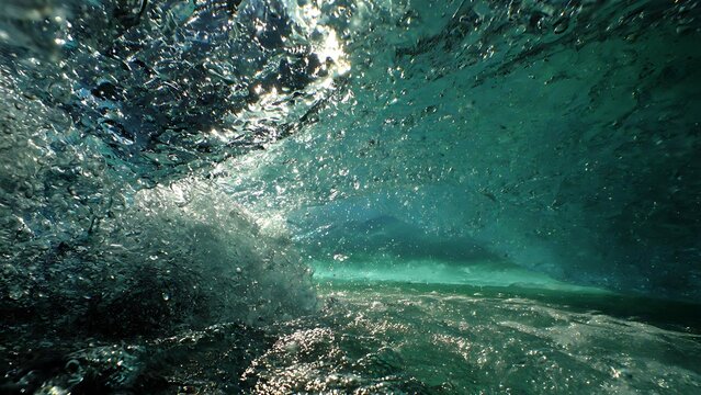 Underwater view of ocean wave crashing and bubbles.