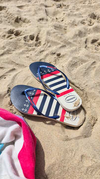 Tarifa, Spain - July 22, 2026: Flip flops on sandy beach with towel nearby