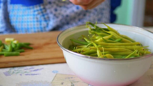 Hand taking fresh green and yellow string beans from a bowl for healthy home meal preparation