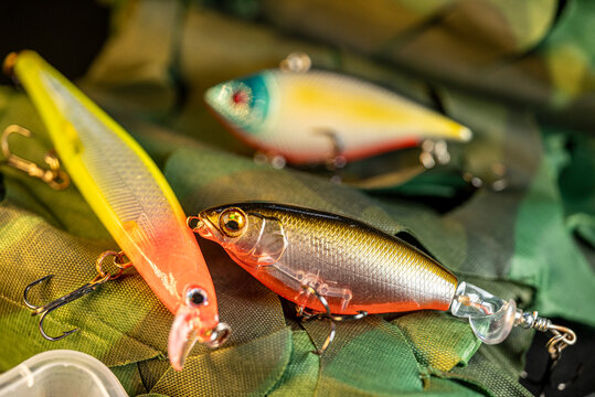 Realistic artificial fish lures resting on camouflage fabric The Concept of sport fishing and outdoor adventure