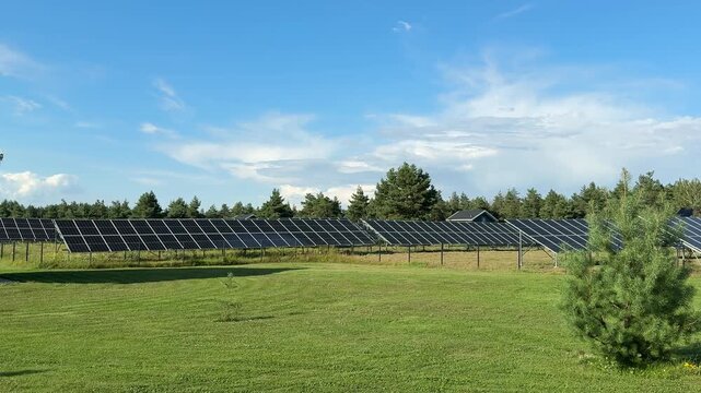 Rows of photovoltaic panels stretch across the landscape beside a detached home, highlighting clean electricity production, self sufficient living, and responsible use of natural resources. Wide shot.