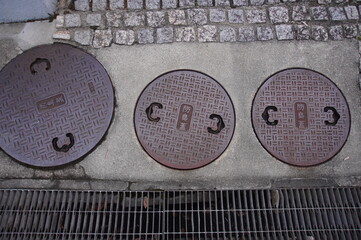 Fototapeta premium Three Japanese iron manhole covers with kanji for odor-proof lid on pavement