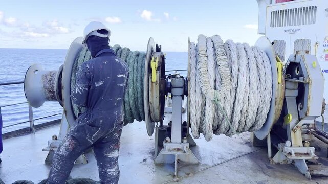 Heavy duty deck operations on commercial cargo ship at sea.