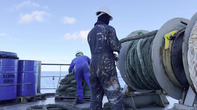 Mariners preparing ship winches and ropes for port entry.