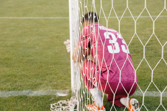 Football goalkeeper preparing for free kick inside goal, soccer goalie getting ready for defense during match concept