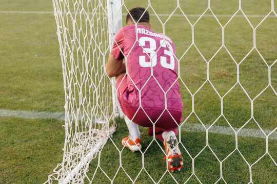 Football goalkeeper preparing for free kick inside goal, soccer goalie getting ready for defense during match concept