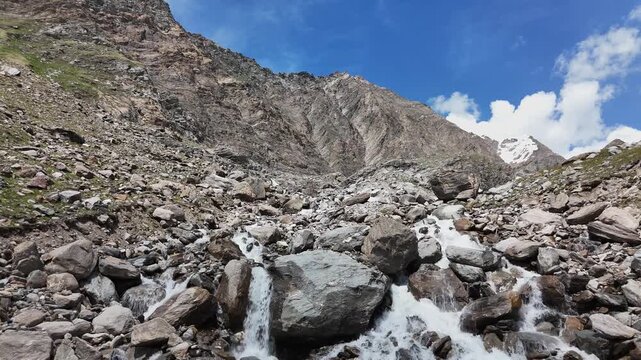 Stunning aerial drone video flying over a rocky alpine stream and massive stone boulders towards steep mountain peaks in the Zillertal Alps.⁠