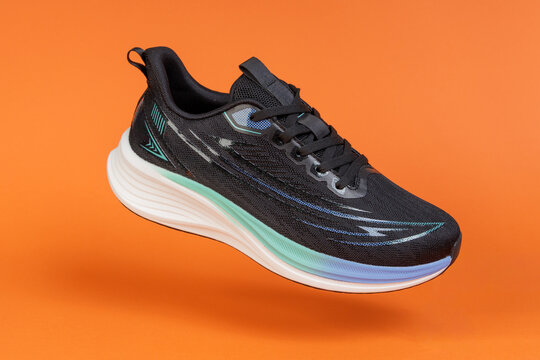 Running shoe levitating on orange background. Modern athletic footwear for fitness, sport, and training. Product photography for e-commerce and advertising.