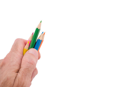 Mano in primo piano che impugna un gruppo di matite colorate in legno per disegnare e attivit&agrave; ricreative, sfondo bianco o trasparente