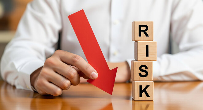 Businessman hand pointing at a falling red arrow near risk blocks, perfect for showing financial danger corporate loss and failure