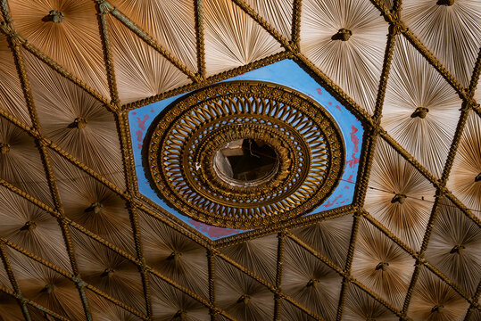 A richly decorated ceiling showcasing intricate geometric patterns with a central circular element. Concept: Luxurious interior design, architecture, decorative arts, architectural beauty.