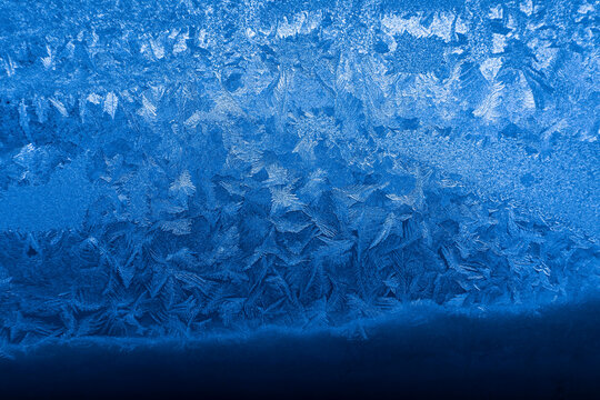 Intricate frost crystals frozen on glass surface creating a beautiful abstract winter pattern
