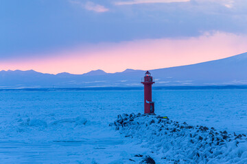 Red lighthouse standing on frozen drift ice in Okhotsk Sea, Hokkaido winter landscape © kei u