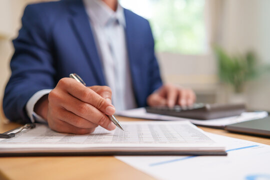 Businessman reviews accounting documents and financial records, highlighting audit procedures, data analysis, tax assessment, and accurate business reporting.