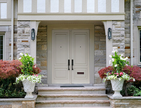 Elegant double front door of Tudor style house with Japanese maple and flowers