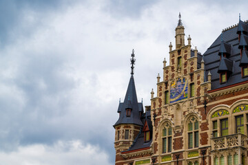 Obraz premium Historic European civic building with decorative tower and colorful clock standing beneath expansive cloudy sky providing generous copy space for design