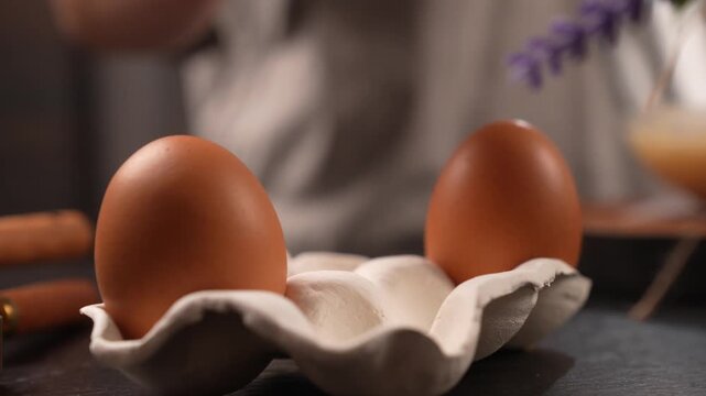 Close-up of a chef's hand picking up a chicken egg.