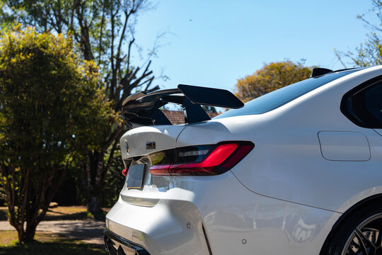 White BMW M3 Competition rear wing and taillight side view, Luxury sports sedan external detail outdoors