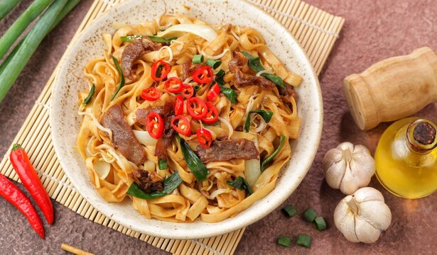 Stir fry Beef Chow Fun with rice noodles, bean sprouts, spring onions and chili.
