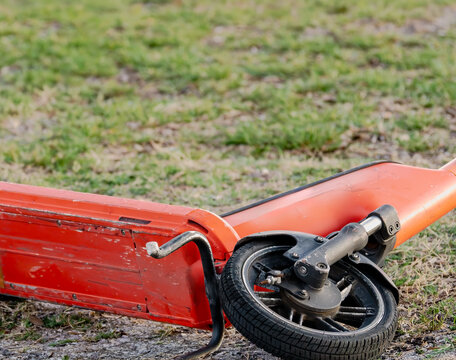 Abandoned electric scooters lying in grass