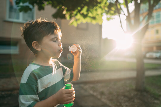 A boy blows a soap bubble in the park during summer