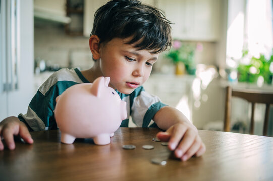 A young boy counts money next to a piggy bank