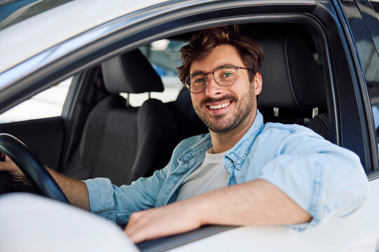 Smiling driver in denim shirt looking at camera during test drive