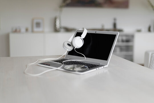 Laptop, headphones and CD on tabletop