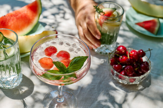 A man holds a refreshing summer cocktail at an outdoor dining table