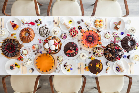 Directly above view of dining table filled with all kinds of snacks and desserts