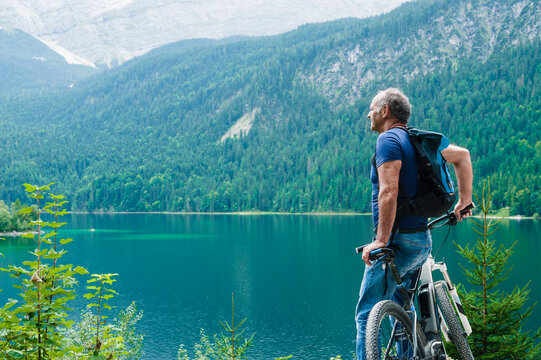 Senior man with e-bike enjoying view over Eibsee