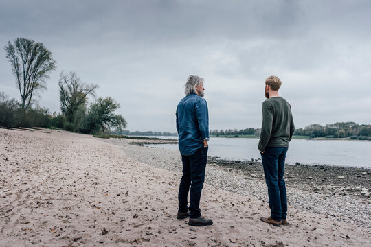 Father and son taking a stroll at Rhine river, meeting to talk