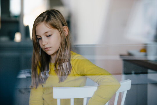 Portrait of a sad girl sitting on chair at home