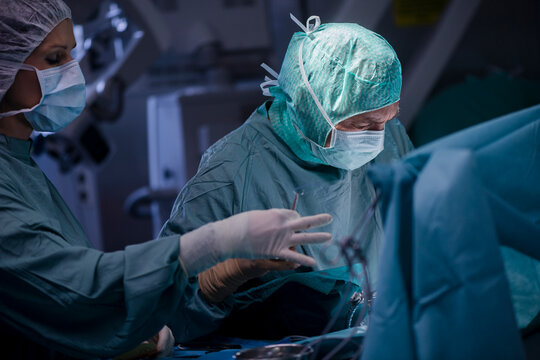 Neurosurgeon with nurse closing operation wound