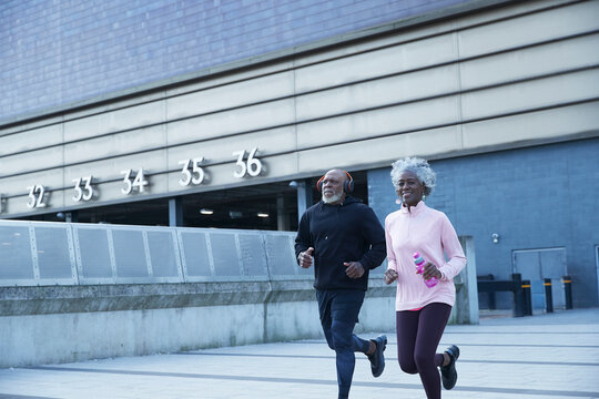 Smiling woman jogging with man in front of building
