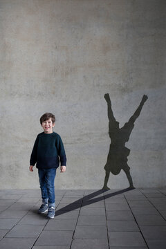 Germany, Duesseldorf, portrait of laughing little boy and shadow of Duesseldorf's cartwheeler on wall