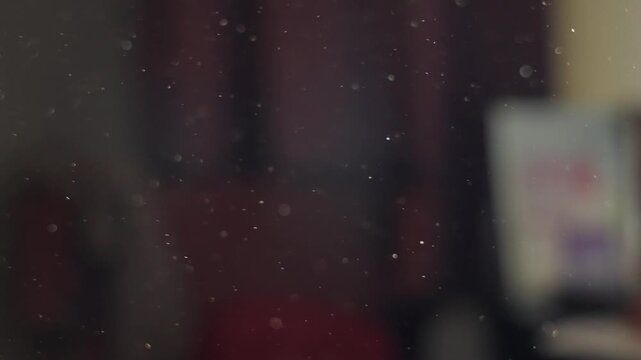 Stuffed room with dust particles flying around in close up in dirty house. Small specks of dust moving in the air as sunlight shining inside closed apartment through window blinds. Old antique place