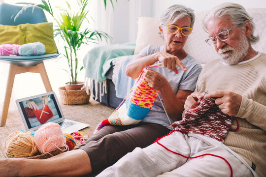 Woman teaching man to knit wool with needle at home
