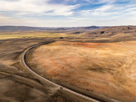A solitary car navigates a remote highland road in Iceland