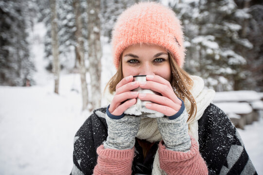 Portrait of young woman drinking hot drink outdoors in winter