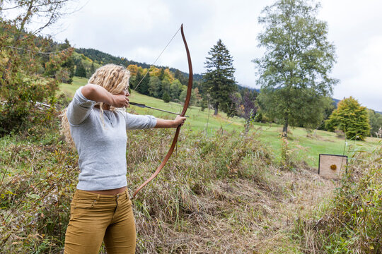Archeress aiming with her bow on target