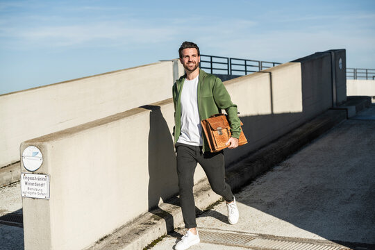 Happy man walking with bag on sunny day