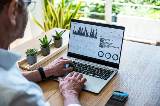 Senior man analyzes financial data on a laptop in the office