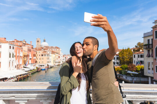 Italy, Venice, happy young couple on a bridge taking a selfie