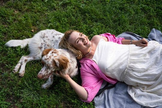 Smiling woman lying with dog in park