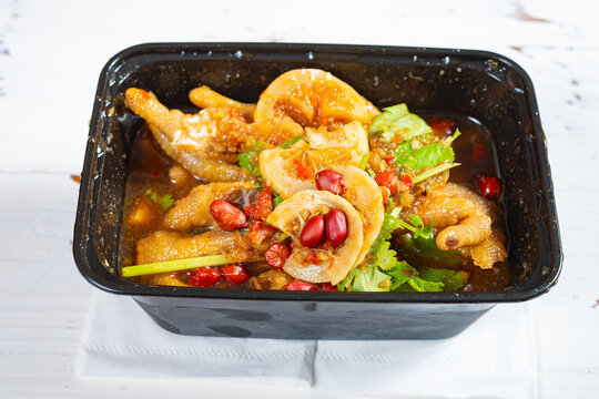 Marinated lemon chicken feet served in black plastic takeout container