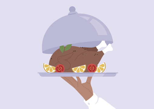 A waiter lifting a metal cloche, revealing a roasted chicken served with herbs and vegetables on a tray