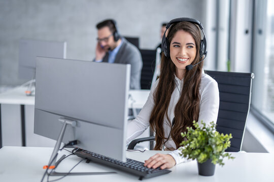 Happy female customer service representative typing on a computer keyboard and looking away